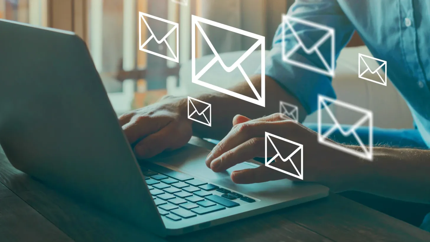 A man using a laptop where virtual envelopes are floating above the laptop
